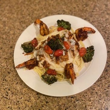 Grilled shrimp and broccoli on pasta with creamy sauce and cherry tomatoes.
