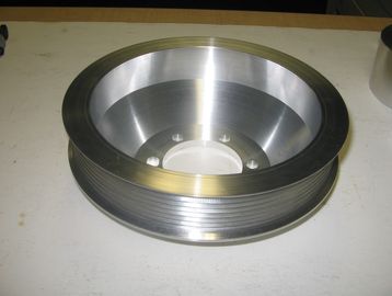 A metallic pulley with grooves on a white surface.