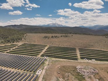 A drone photo with a mountainous scene with a solar array in the foreground