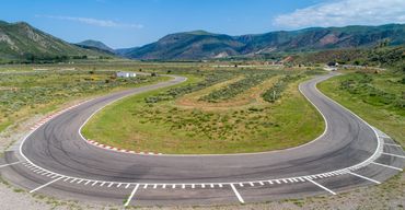 Drone Photo of a hairpin turn on a racetrack with a mountainous horizon and blue skies