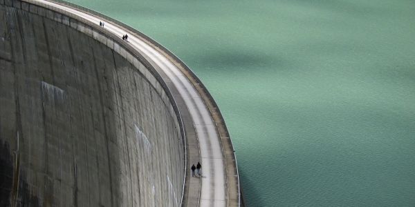 Two pairs of people walking on a curved dam pathway.