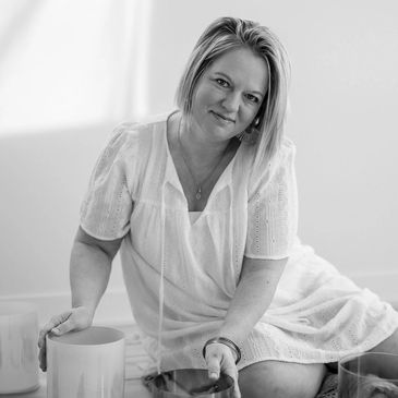 Woman in a white dress sitting and smiling in a bright room.