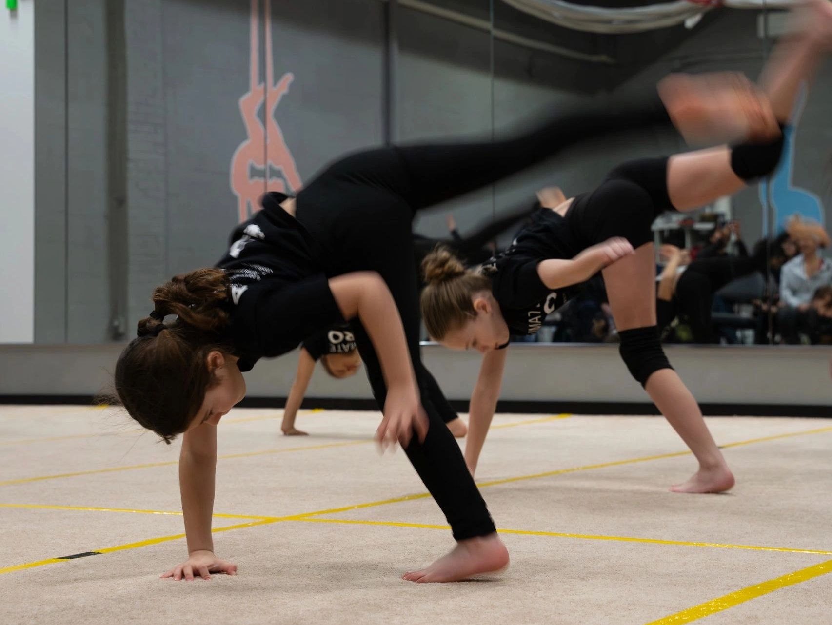 Young girls practicing gymnastics moves indoors.