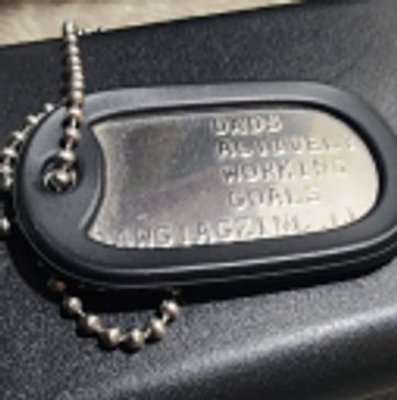 A close-up of a metal military dog tag on a ball chain.