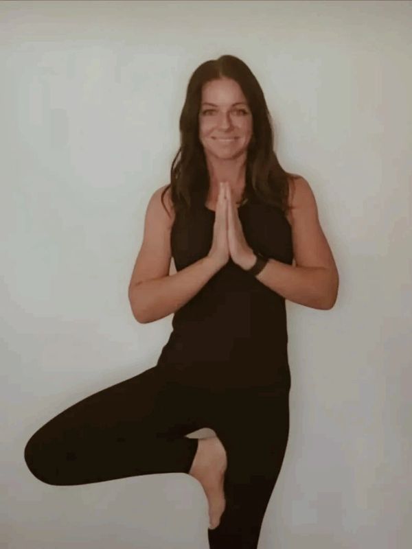 Woman practicing yoga in tree pose with hands in prayer.
