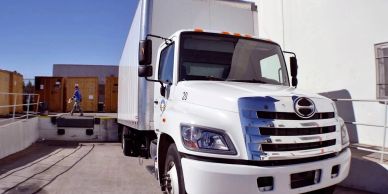 White delivery truck parked beside a loading dock on a sunny day.