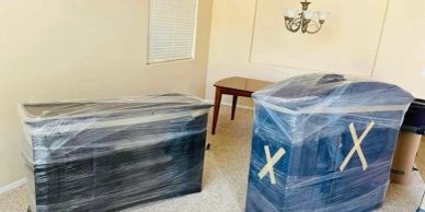 Two large pieces of furniture wrapped in plastic in a room.