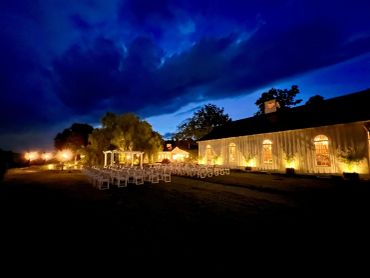 Outdoor evening wedding setup with lights and chairs.