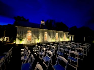 Outdoor event seating at night in front of a lit building.