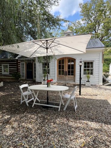 Outdoor patio table with umbrella and chairs in front of a house.