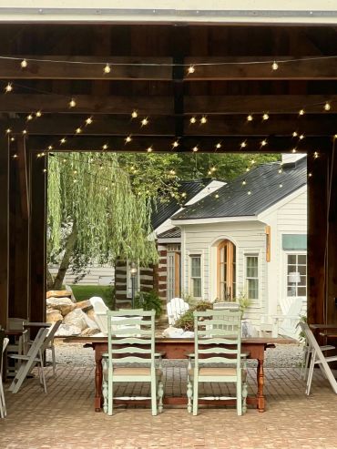 Outdoor dining area with string lights and pastel chairs.