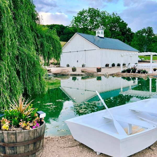 A peaceful view of the beautiful barn and rowboat by the pond—just one of the many charming backdrops at Spring Tavern Farm.