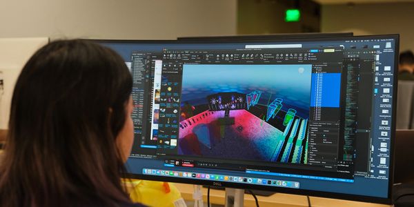 Person working on 3D game design using Roblox Studio on a large monitor.