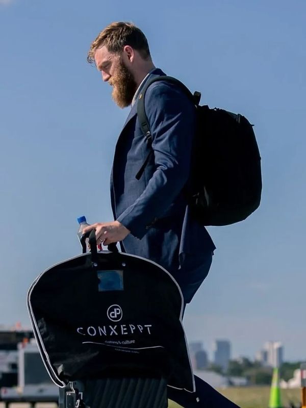 Man wearing a custom tailored business suit holding a Conxeppt garment bag