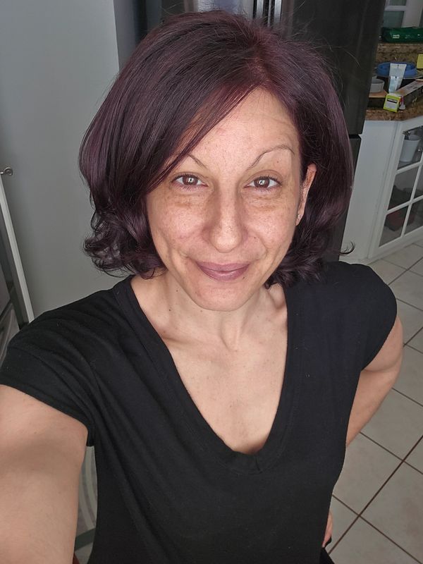 Woman with short dark hair smiling indoors in a casual black top.