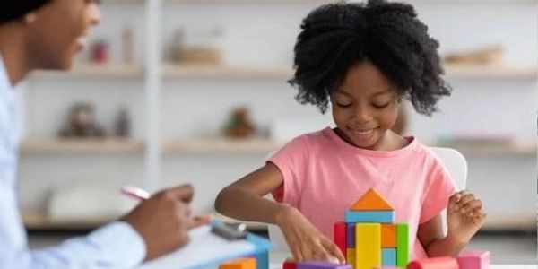 A young girl happily playing with colorful building blocks.
