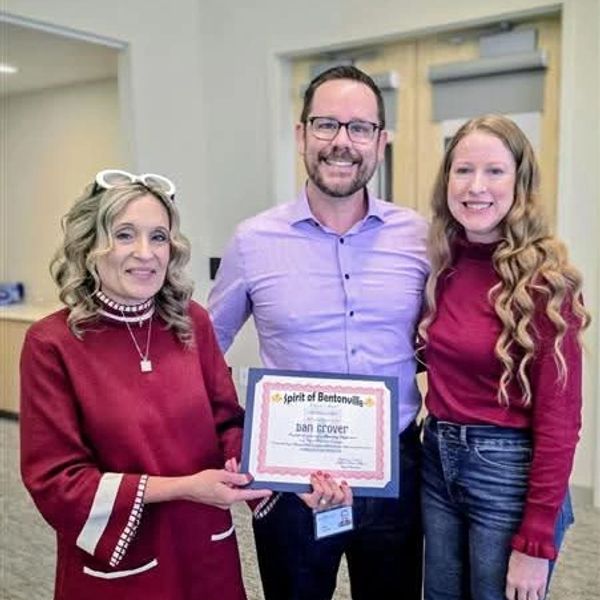 Three people posing with a certificate indoors.