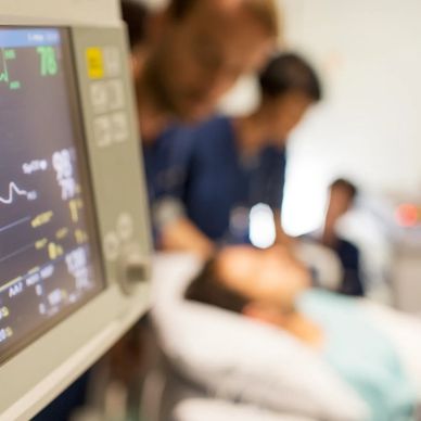 Hospital scene with vital signs monitor and patient in bed.