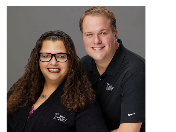 A smiling man and woman wearing matching 3 Pillar Homes shirts.
