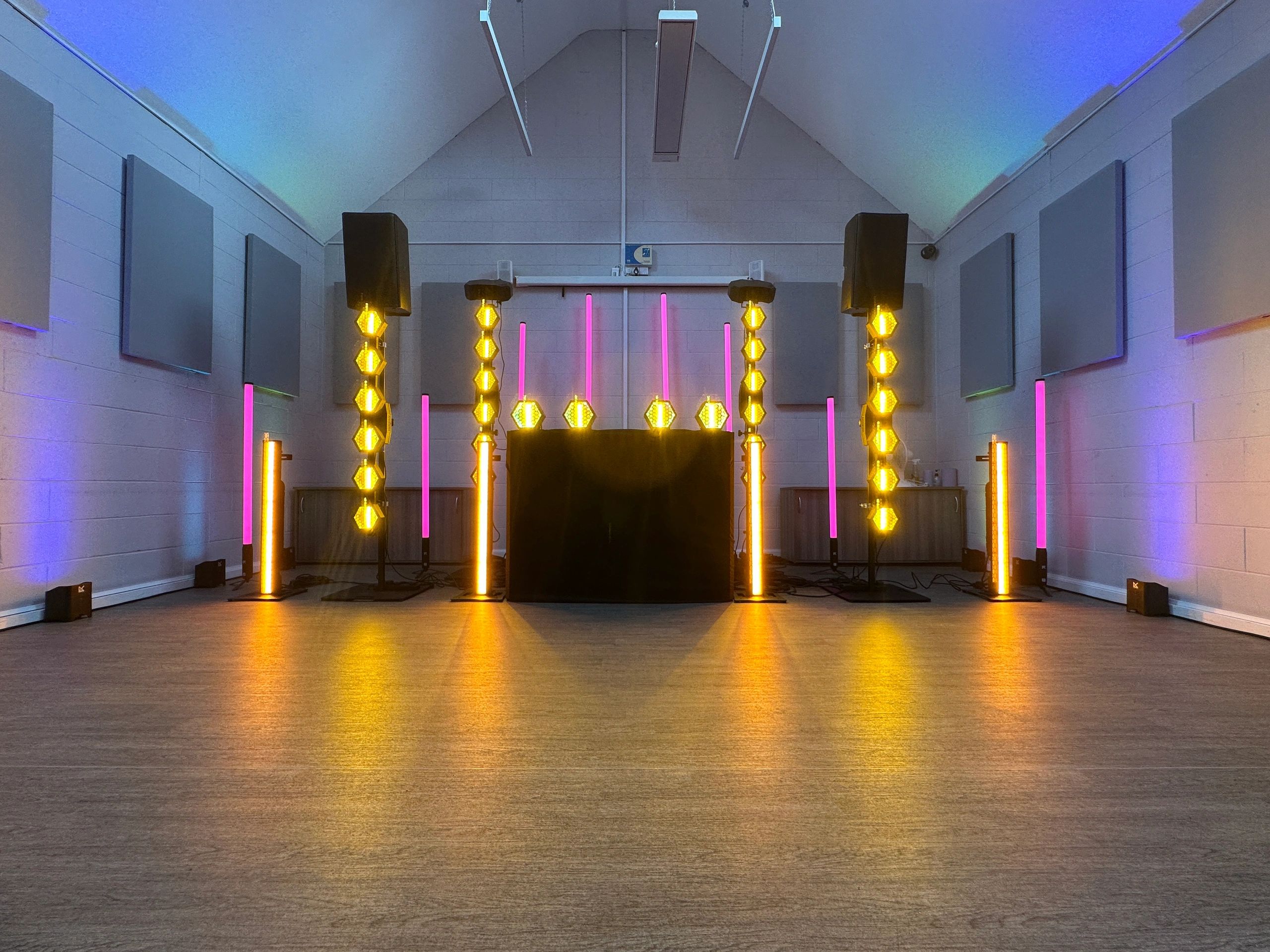 Modern DJ setup with colorful lights in a hall.