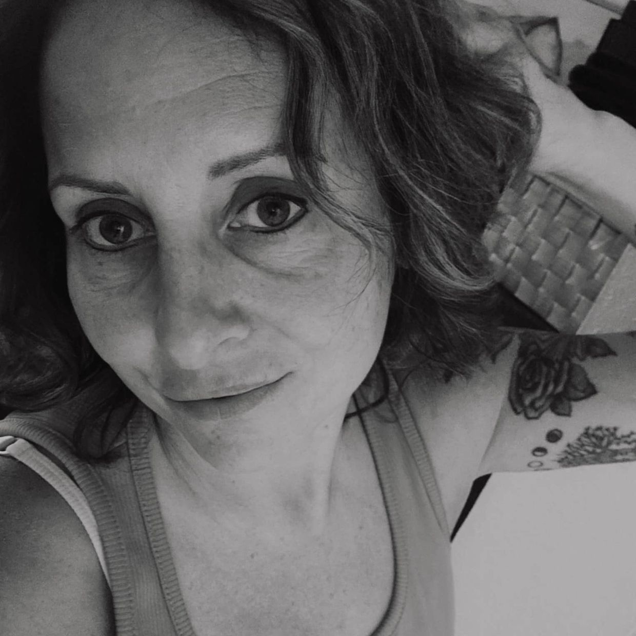 Black and white selfie of a woman with a tattoo on her arm.