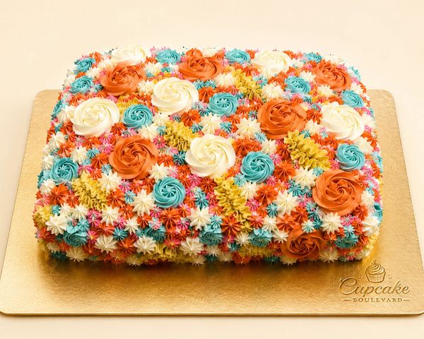 Colorful rectangular cake decorated with intricate floral frosting in orange, white, and blue.