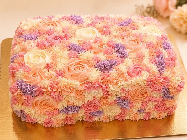 A rectangular cake decorated with pastel-colored buttercream flowers.