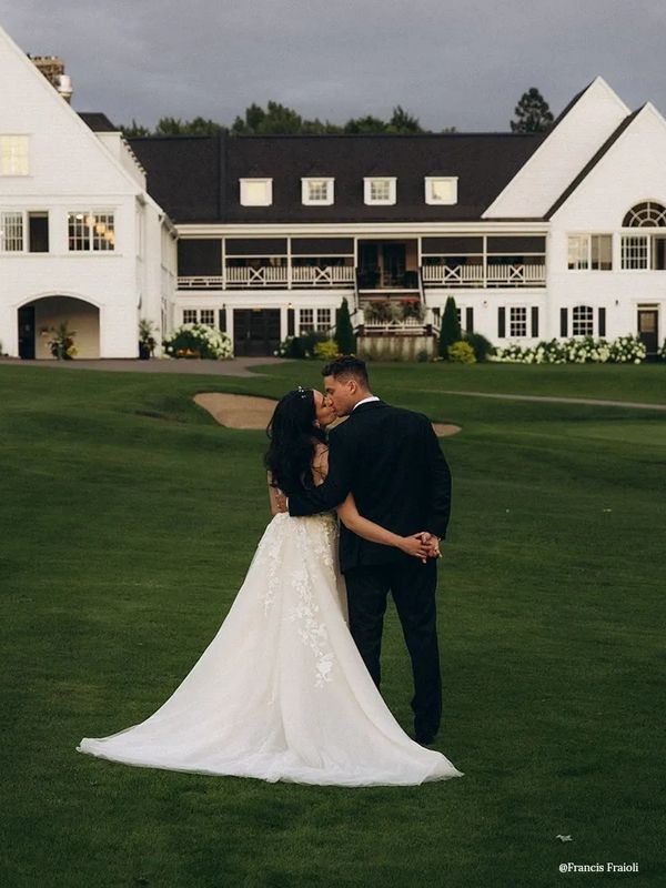 Un couple qui s'embrasse devant un bâtiment de style Cape Cod, Hamptons, architecture coloniale.
