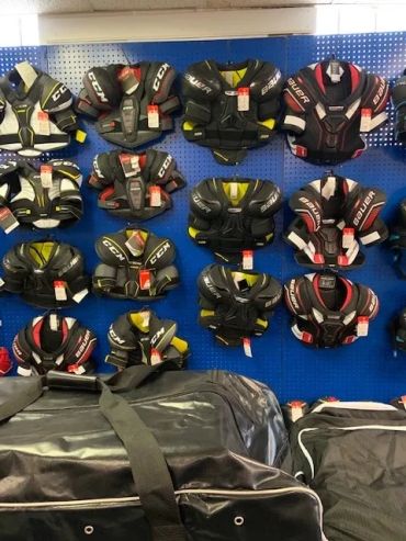 Wall display of various hockey shoulder pads in a sports store.