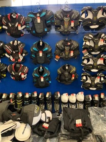 Hockey protective gear displayed on a blue pegboard in a store.