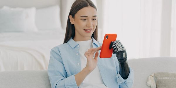 Woman with a prosthetic hand using a smartphone and smiling.