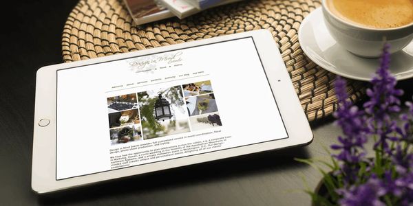 Tablet displaying a website, placed on a woven placemat with coffee and flowers nearby.