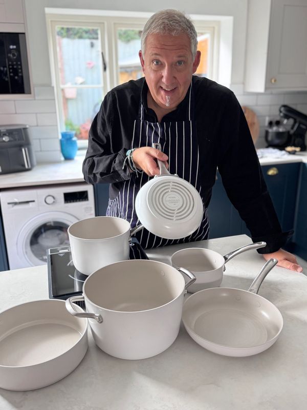 Man in kitchen showing white cookware.