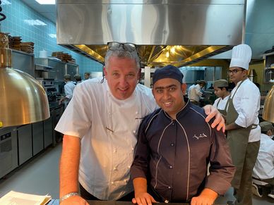 Two chefs posing together in a professional kitchen.