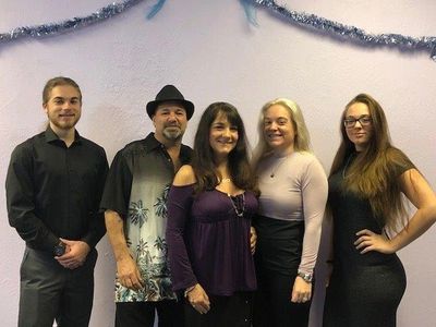 Group of five adults posing in front of a decorated wall.