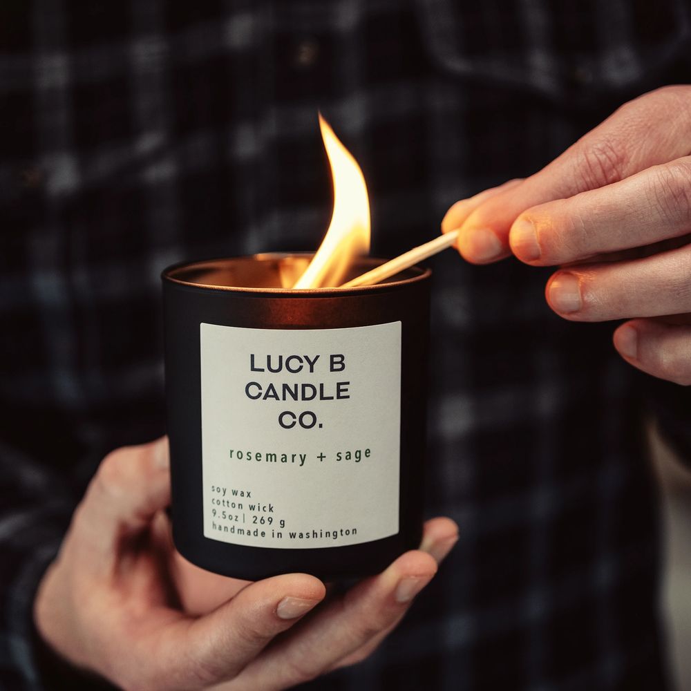 Hands holding a candle while lighting the wick with a match.