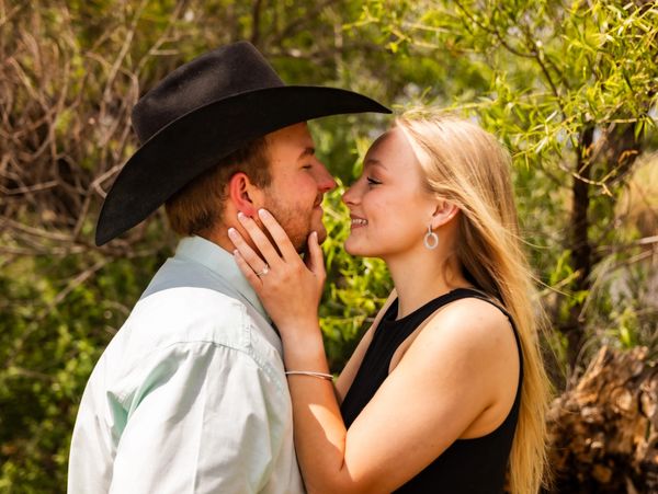 A couple sharing a tender moment outdoors, smiling and close to kissing.