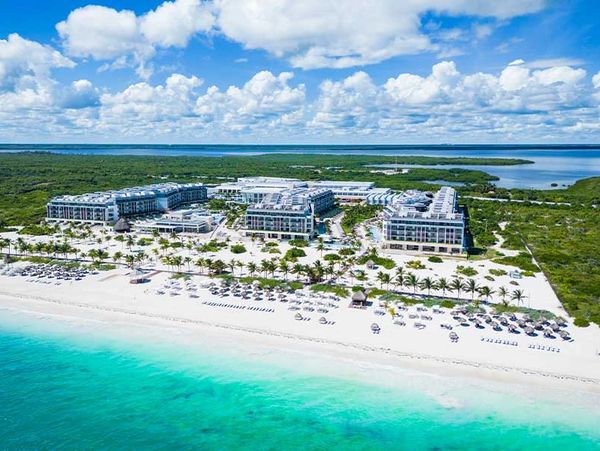 Aerial view of a beachfront resort with turquoise waters and white sand.
