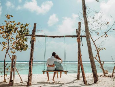Romantic beach getaway with a couple on a swing. Honeymoon Travel Advisor