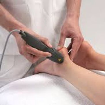 A medical professional using an ultrasound device on a patient's ankle.