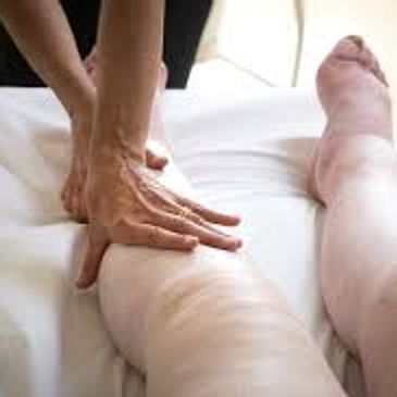 Hands massaging swollen legs on a bed.