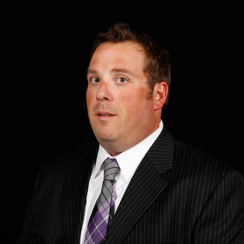 Man in a black pinstripe suit with a purple plaid tie.