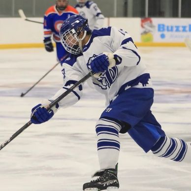 Young ice hockey player hitting the puck.
