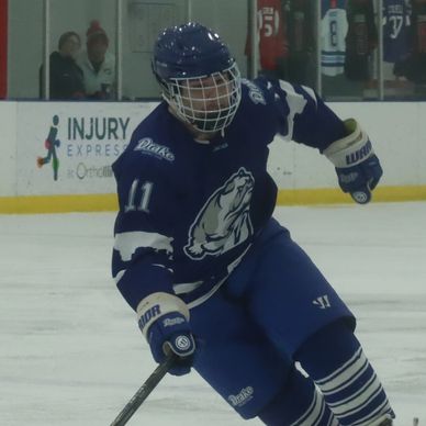 Ice hockey player in blue jersey skating on ice.