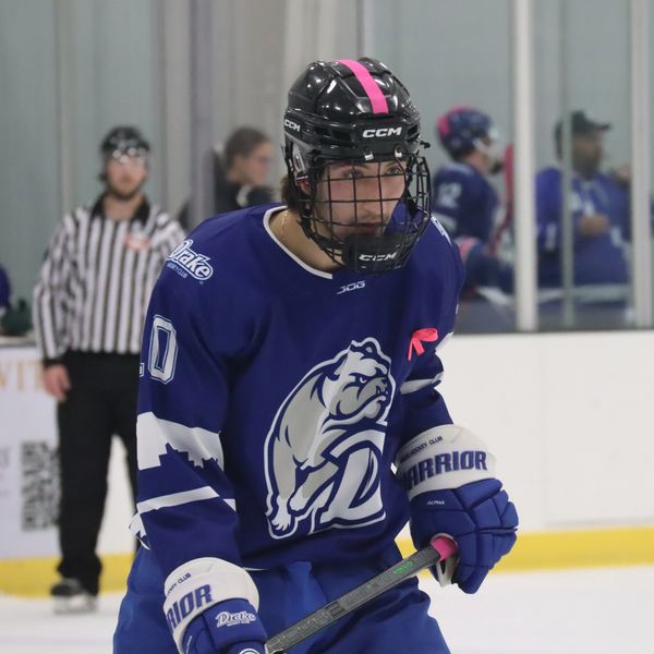 Ice hockey player in blue jersey focused on the game.