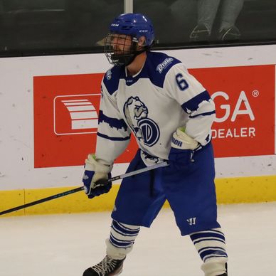 Hockey player in blue and white gear on ice rink.