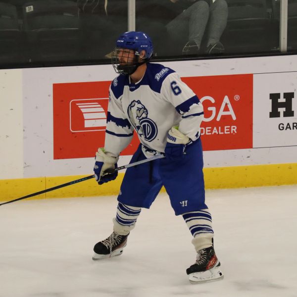 Ice hockey player in white and blue uniform on the ice.
