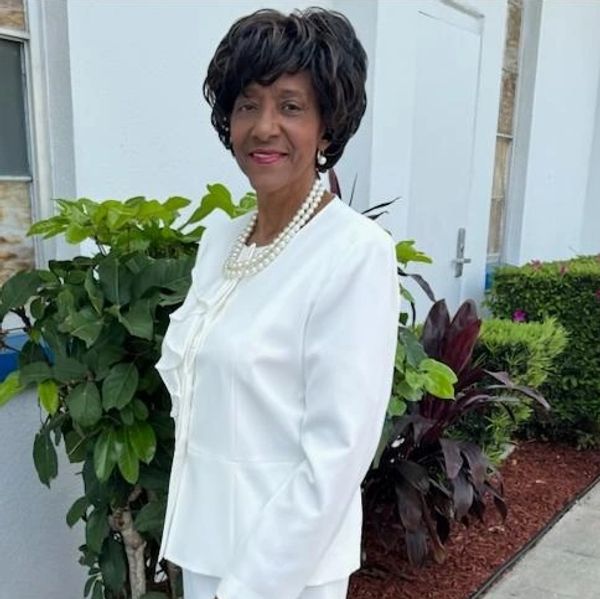 Elegant woman in white outfit with pearl necklace.