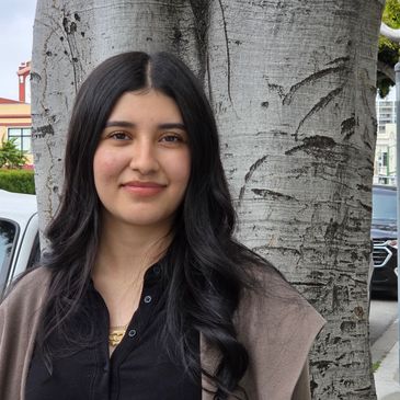 Fatima stands outside by a tree