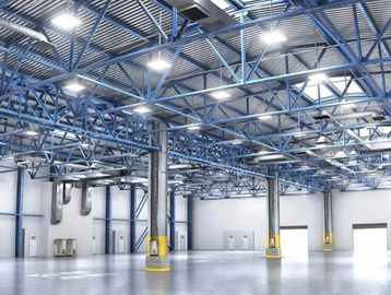 Spacious, empty industrial warehouse with blue steel ceiling beams and bright lighting.